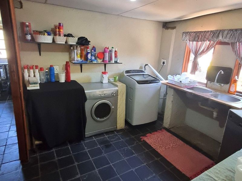 Functional laundry room featuring tiled flooring, a double basin sink, and dedicated plumbing connections for appliances.