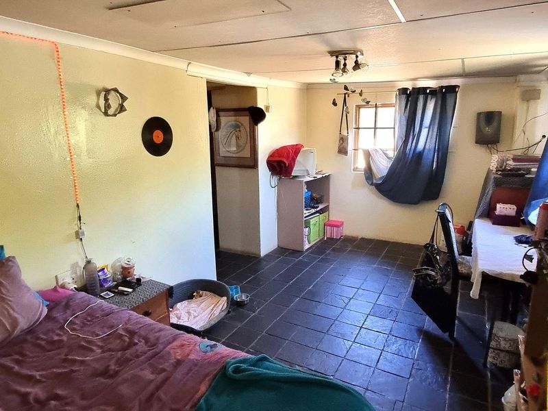 A bedroom featuring dark tiled flooring and a coved ceiling, requiring cosmetic updates to improve the overall finish and appeal.