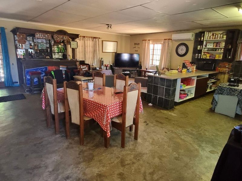 Spacious open-plan living area featuring a built-in bar, kitchen island with tiled finish, and direct access to the outdoor patio area.
