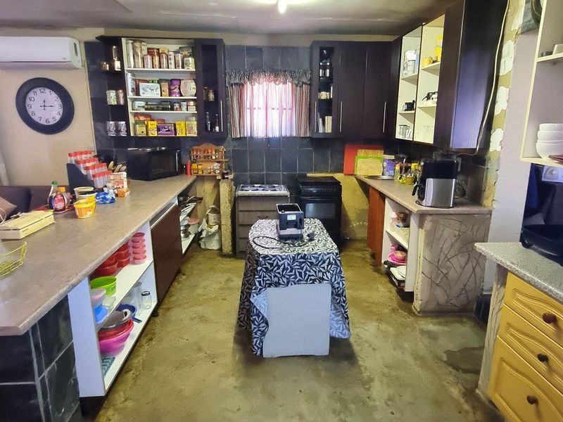 Open plan kitchen and living area featuring built-in cabinetry, a breakfast counter, and air conditioning, requiring cosmetic updates to improve the overall finish.