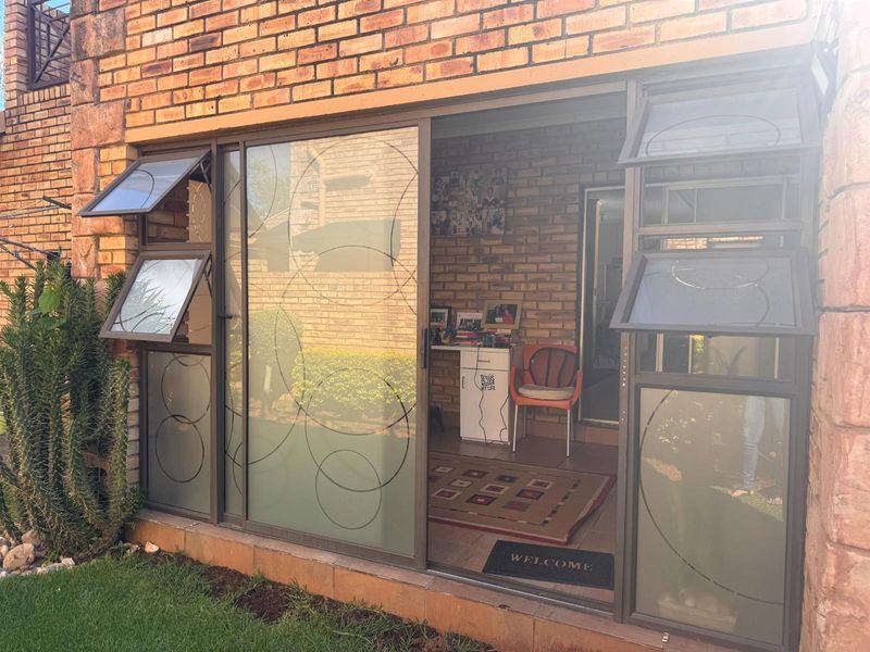 A covered patio area featuring exposed brick walls, tiled flooring, and large sliding glass doors with decorative frosted patterns.