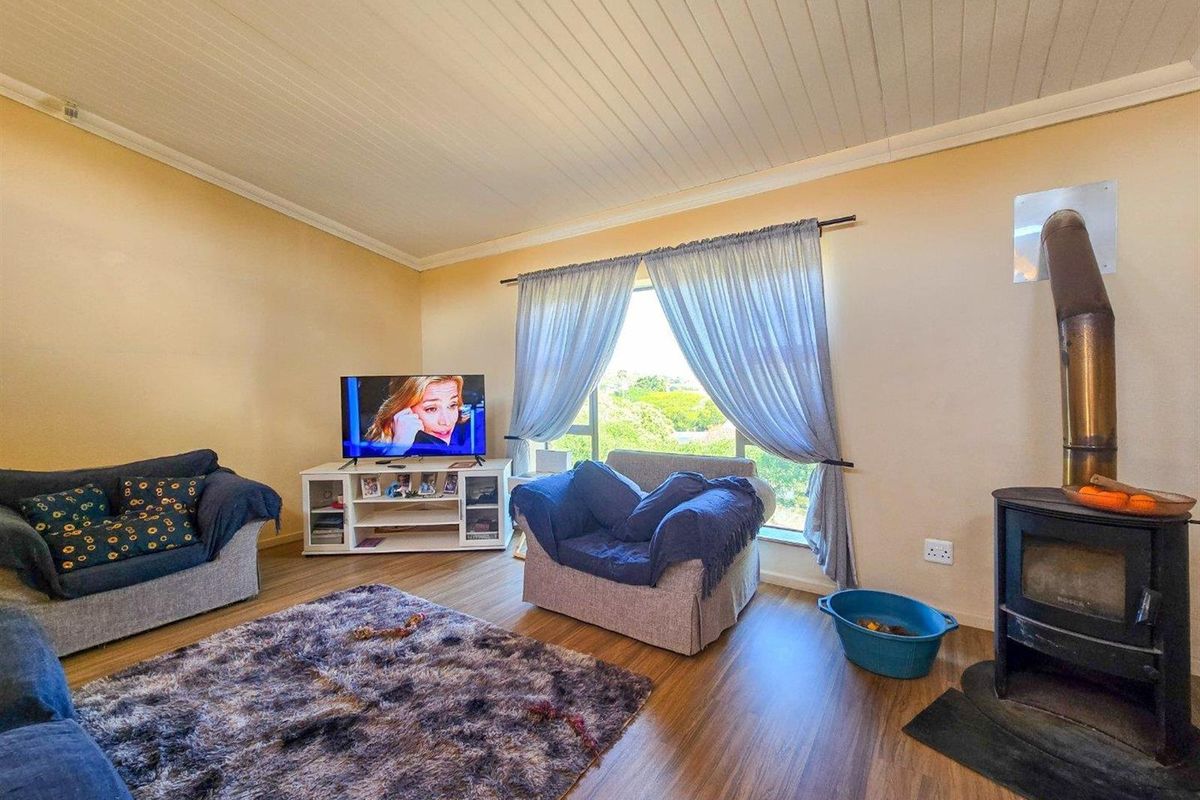 A cozy living room featuring a built-in wood-burning fireplace, wood-look laminate flooring, and a large window providing natural light.