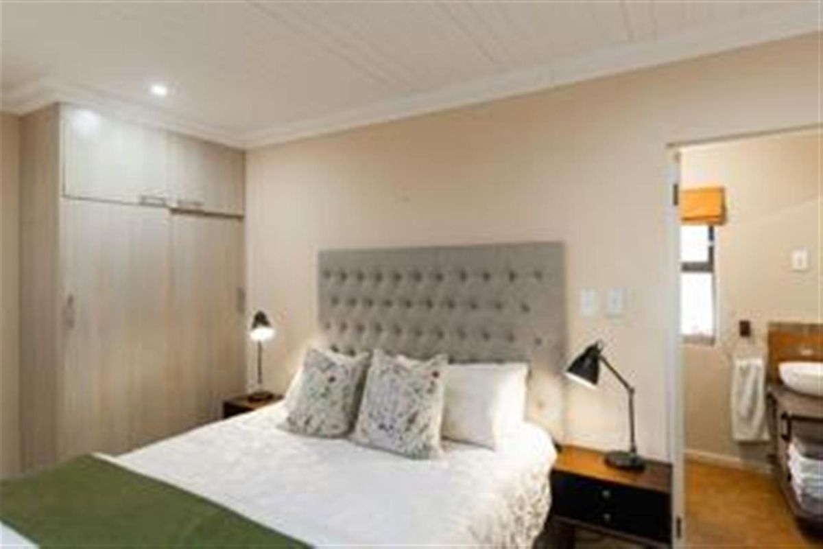 A well-maintained bedroom featuring built-in cupboards and an en-suite bathroom with a modern vanity.