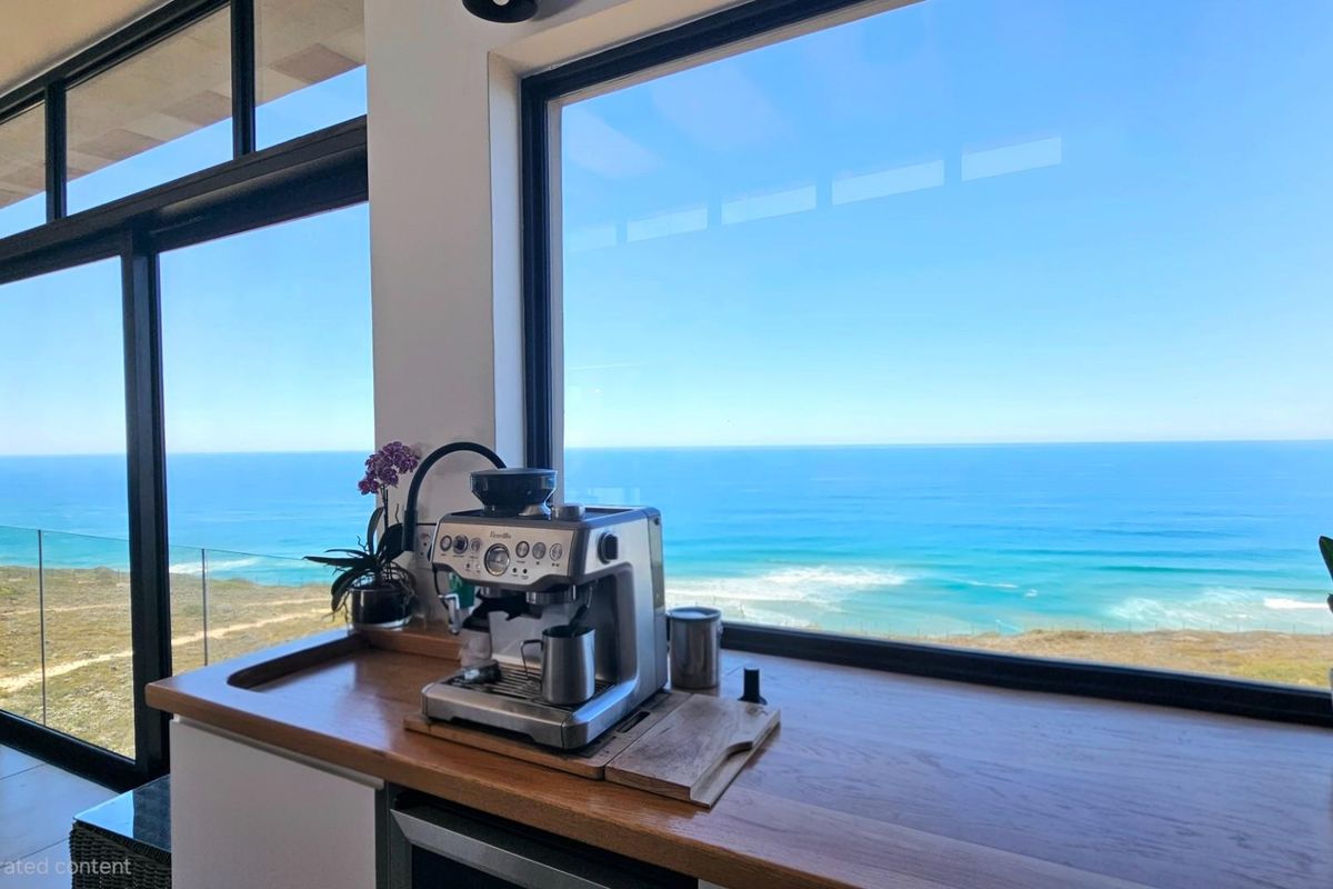 A modern kitchen counter area featuring a wooden countertop and expansive floor-to-ceiling windows offering panoramic ocean views.