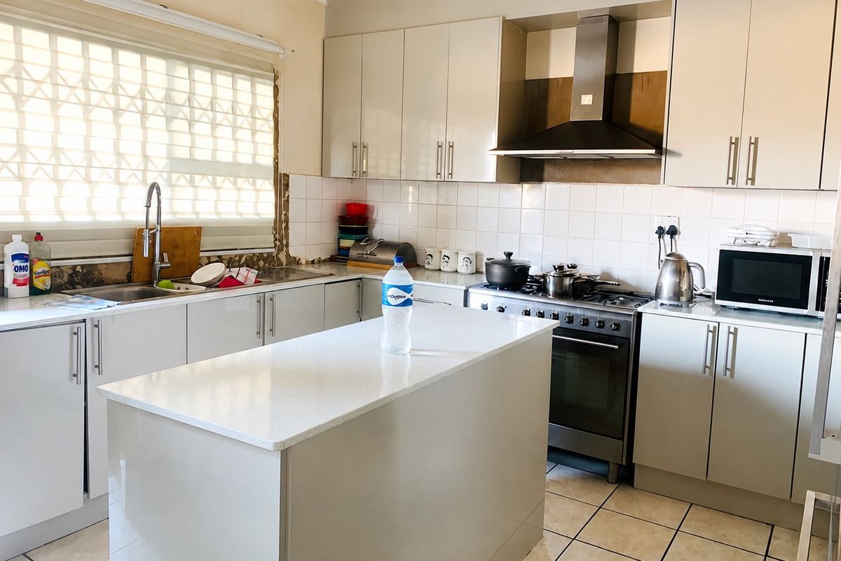 Functional kitchen featuring a central island, stainless steel gas stove with extractor fan, ample cabinetry, and tiled flooring.