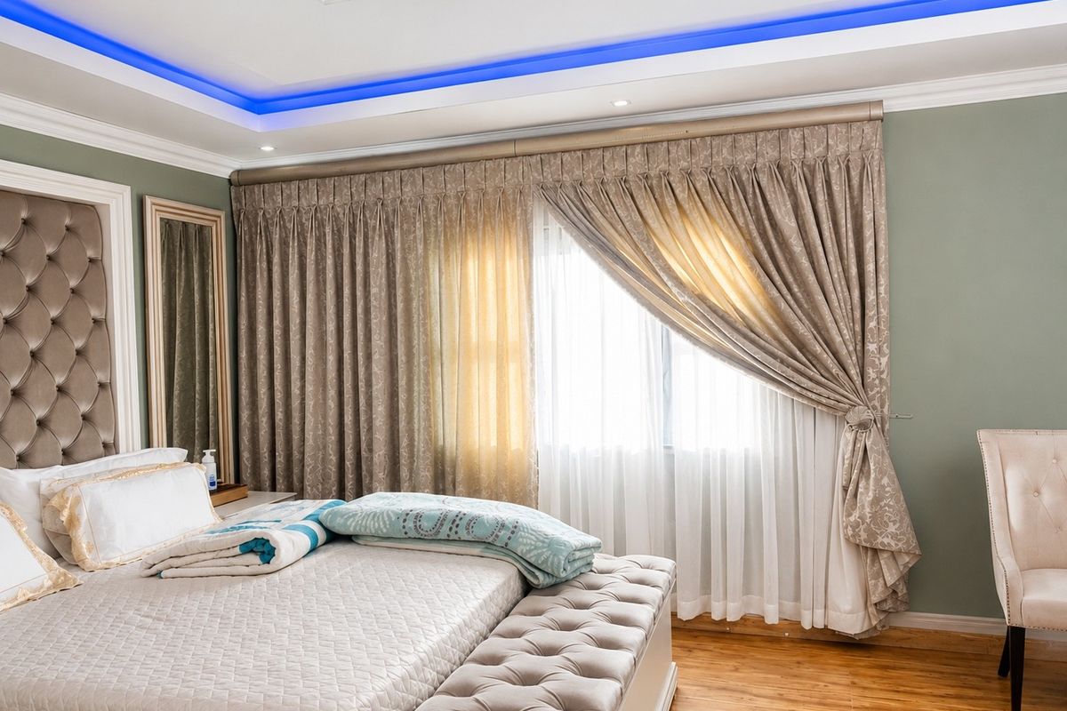 A well-appointed bedroom featuring hardwood flooring, a custom tufted headboard, and a recessed ceiling with integrated blue LED accent lighting.