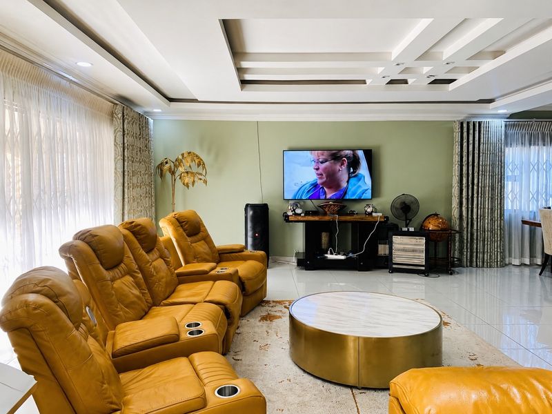 Spacious living room featuring a modern recessed ceiling design, large format floor tiles, and neutral wall tones, creating a comfortable and well-maintained living space.