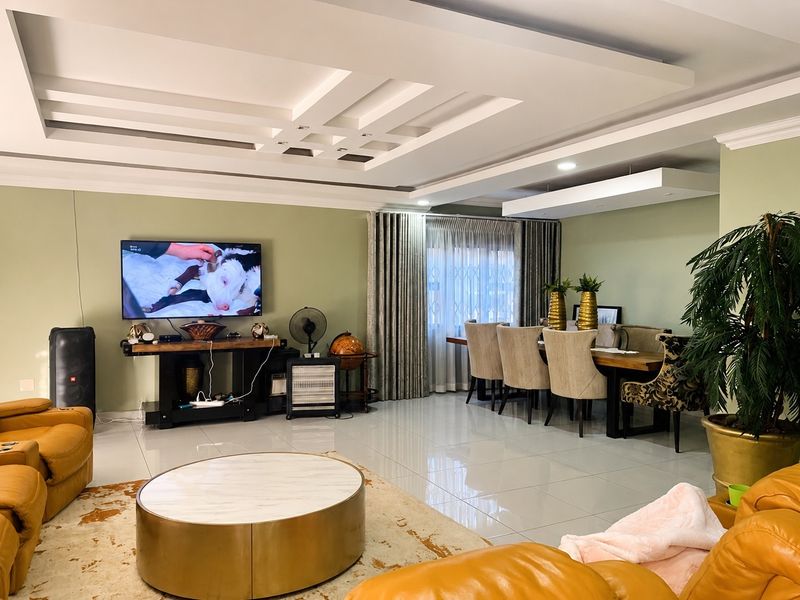 Spacious open-plan living and dining area featuring modern recessed ceiling details, large format floor tiles, and neutral wall finishes.