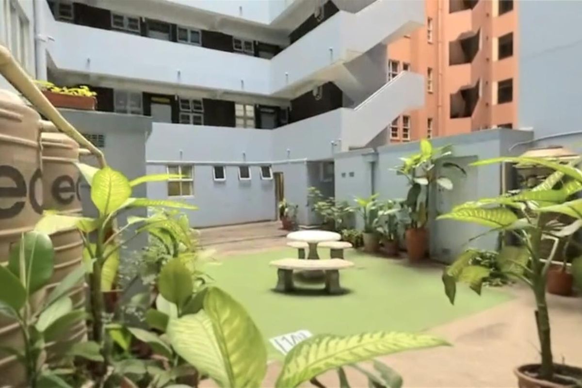 A communal courtyard area within an apartment complex, featuring paved surfaces, external staircases, and water storage tanks.