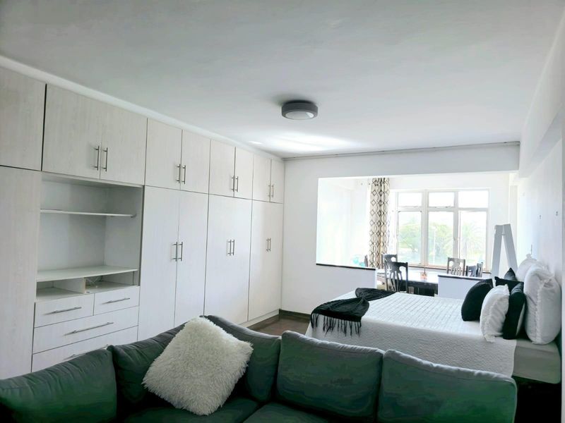 Spacious bedroom featuring extensive built-in cabinetry for storage and a large window that allows for ample natural light.