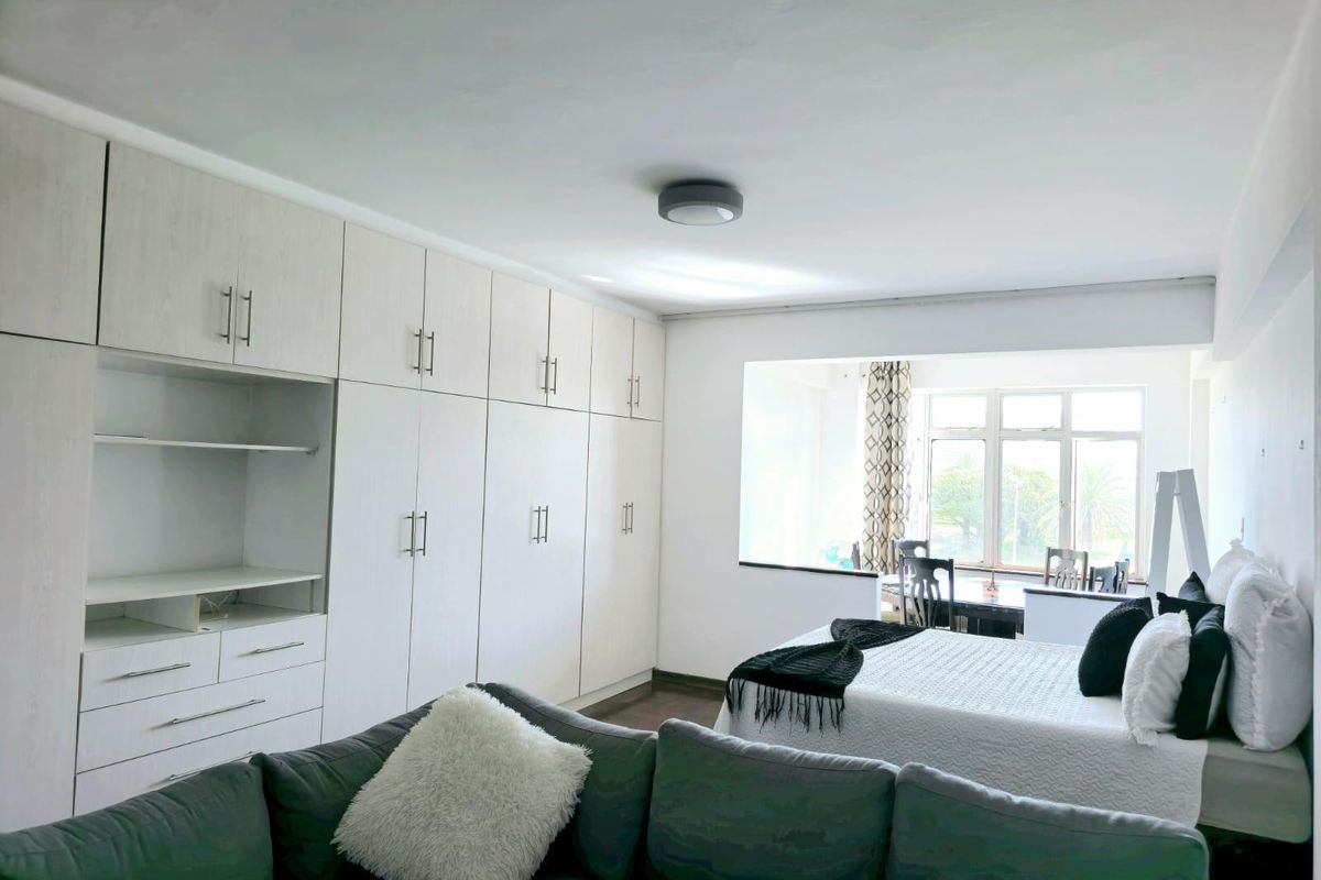 Spacious bedroom featuring extensive built-in cabinetry for storage and a large window that allows for ample natural light.