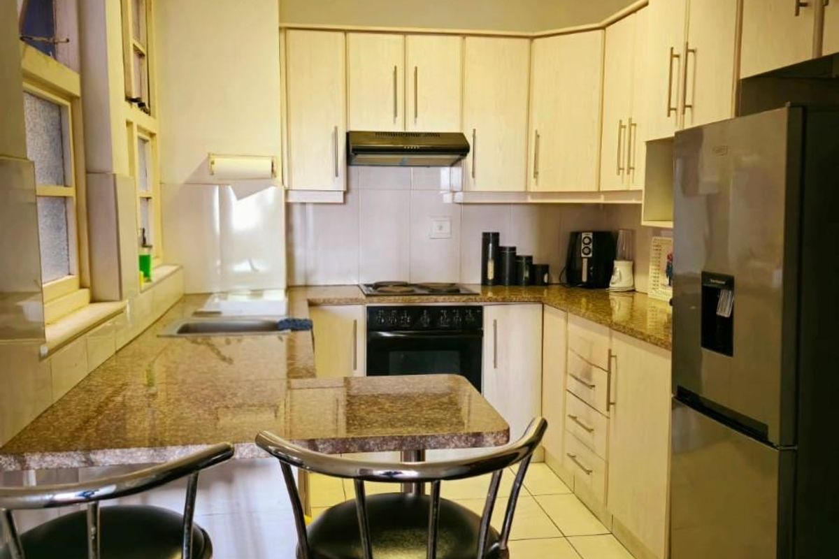 Functional kitchen featuring granite countertops, built-in cabinetry, integrated oven and hob, and tiled flooring, offering a practical layout for daily meal preparation.