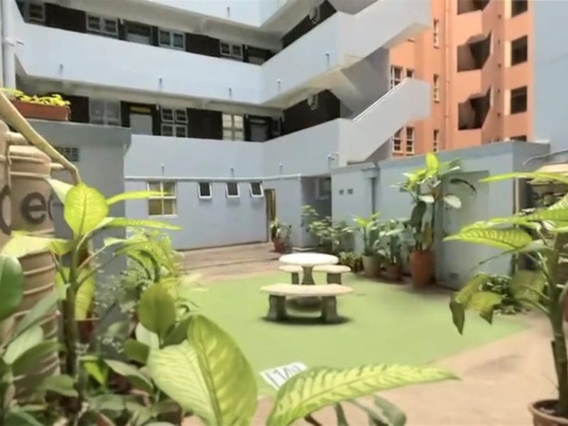 A communal courtyard area within an apartment complex featuring paved surfaces, water storage tanks, and access to external staircases.