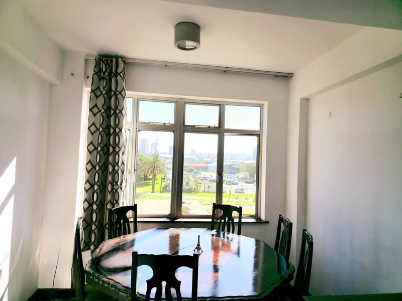 A dining area featuring large aluminium-framed windows that provide natural light and views of the surrounding area.