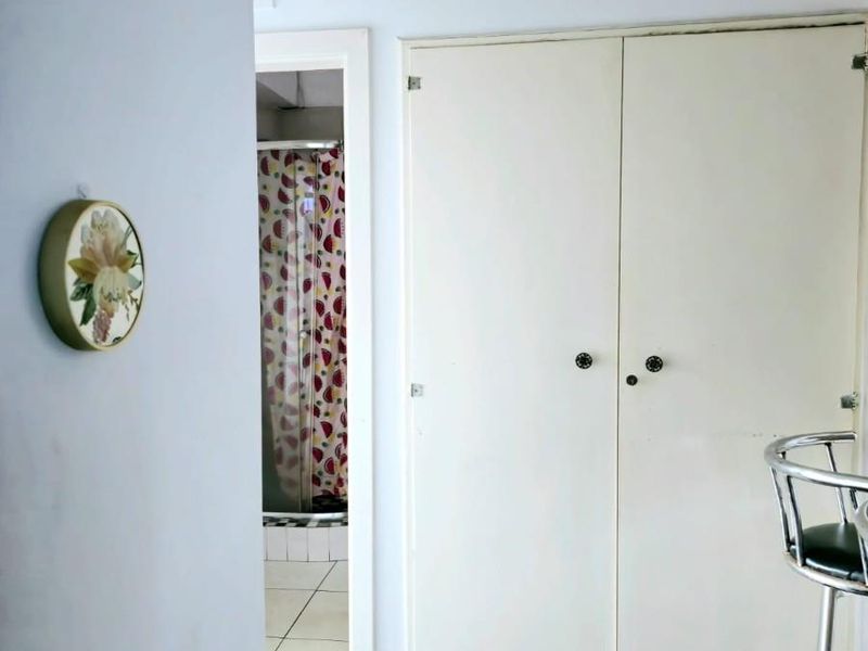 A hallway featuring built-in storage cupboards and traditional parquet flooring, with a view leading into an adjacent bathroom.