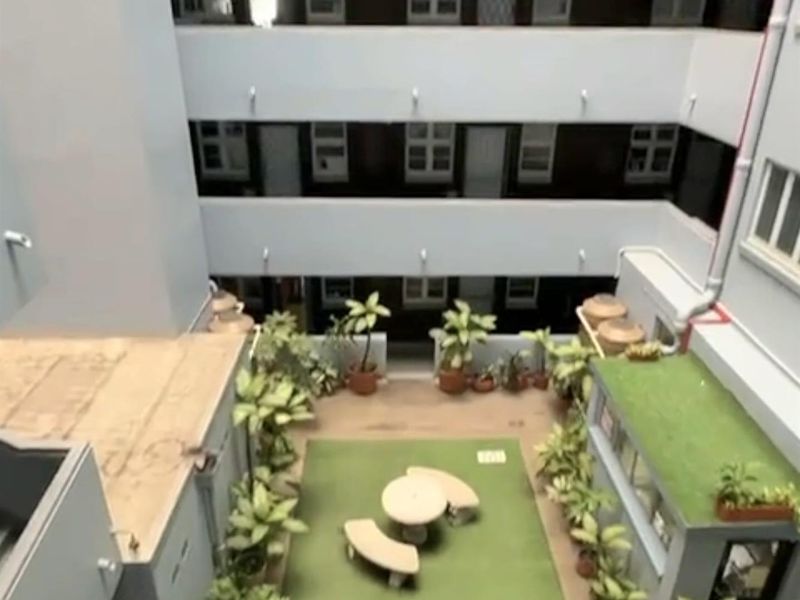 An elevated view of a central apartment courtyard featuring multi-level walkways and a small communal outdoor area with artificial turf.