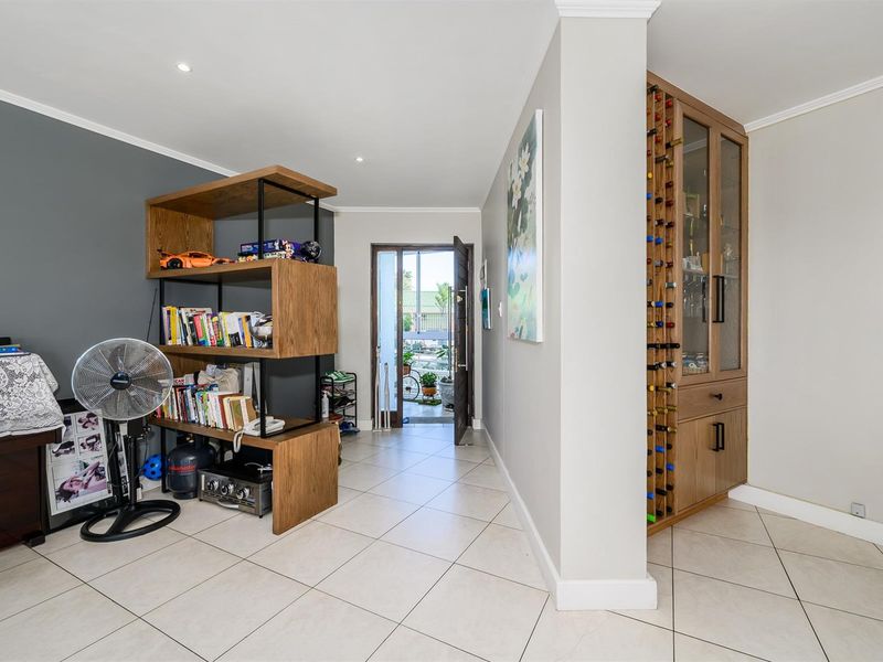 An inviting entryway featuring tiled flooring, recessed ceiling lighting, and a custom built-in wooden wine storage cabinet.