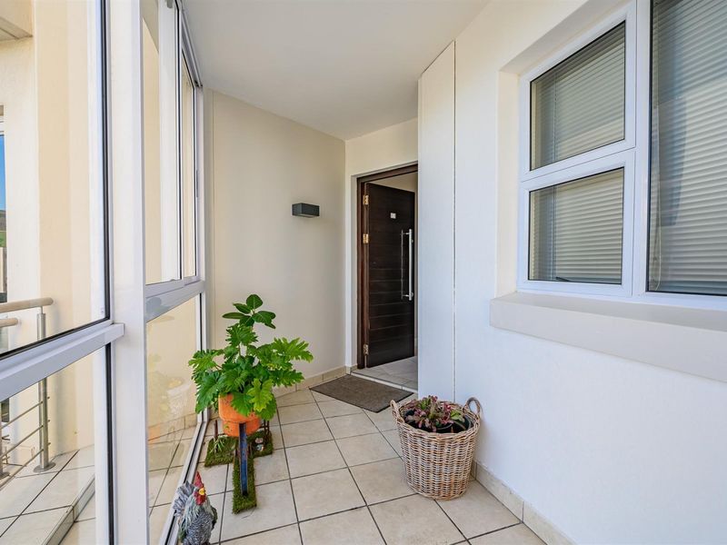 A bright, tiled entrance area featuring large glass windows and a secure front door, providing a welcoming transition into the apartment.
