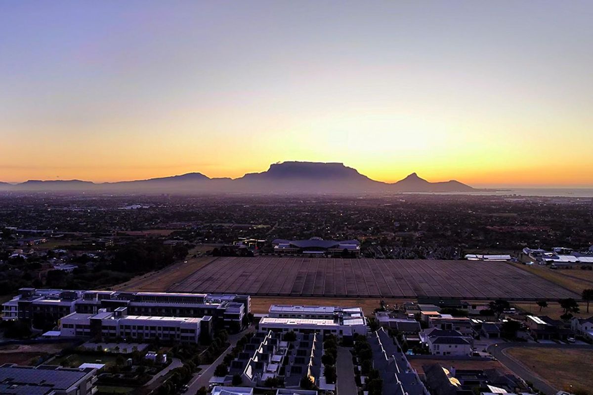 An expansive aerial view showcasing the surrounding landscape and distant mountain range at sunset.