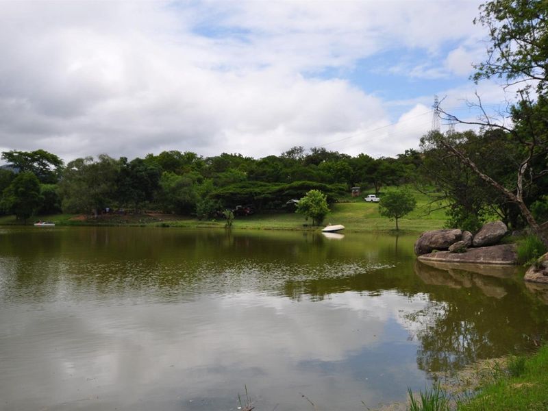 A scenic view of a natural dam on the property, featuring large rock formations and established surrounding greenery.