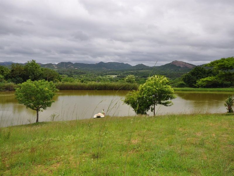 A scenic view of a private dam on the small holding, featuring expansive green lawns and distant mountain vistas.