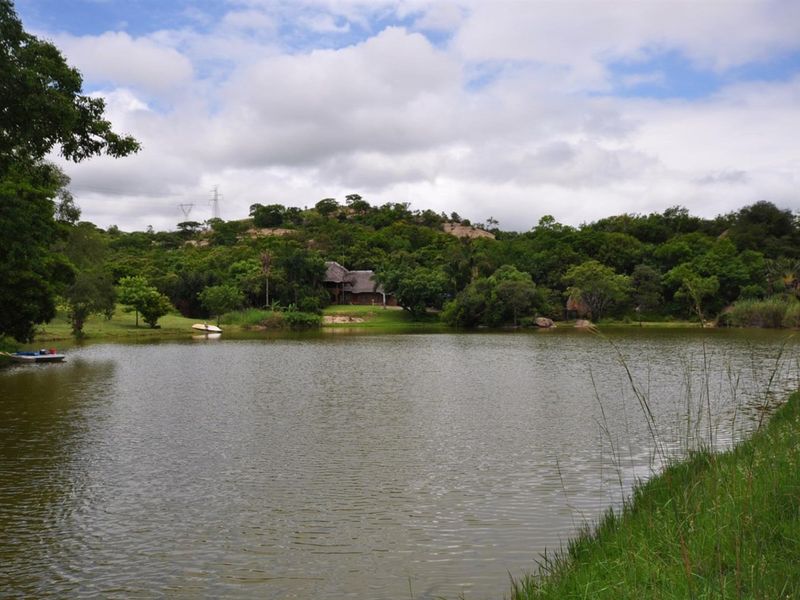 A scenic view of a large dam on the small holding, surrounded by lush indigenous vegetation and natural landscape.
