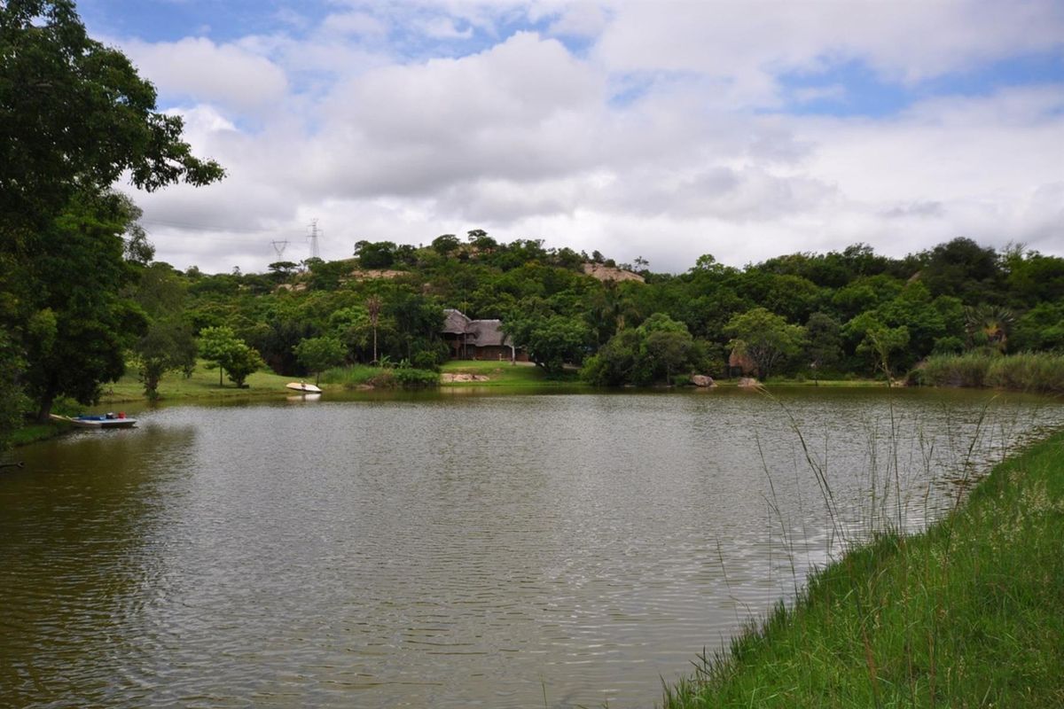 A scenic view of a large dam on the small holding, surrounded by lush indigenous vegetation and natural landscape.