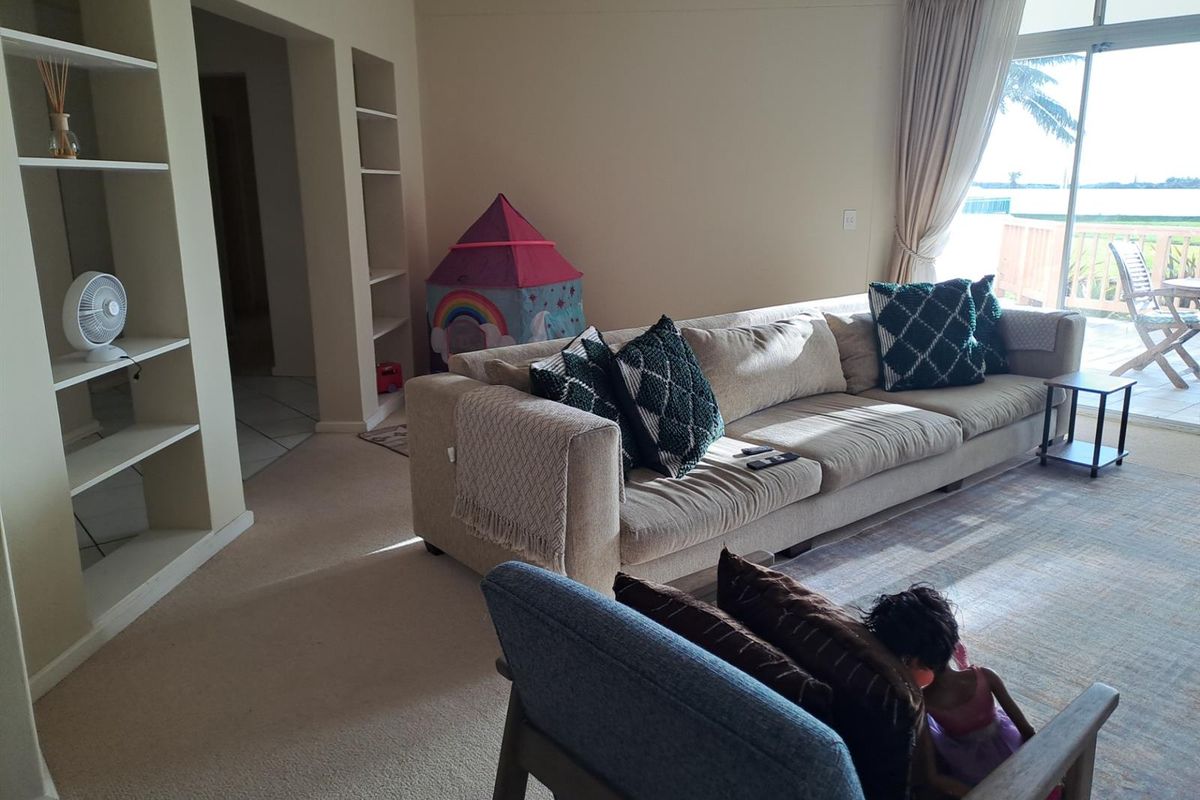 Spacious living room featuring built-in shelving units, neutral carpeting, and large sliding glass doors providing access to an outdoor balcony area.