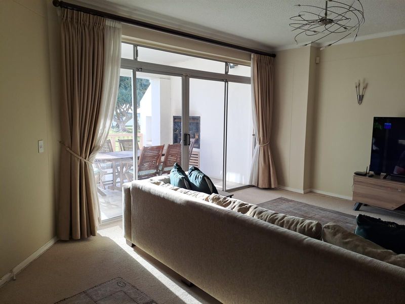 Spacious living room featuring large sliding glass doors that open onto a covered patio, providing natural light and seamless indoor-outdoor flow.