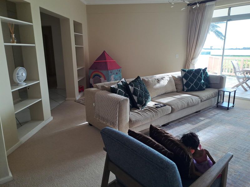 Spacious living room featuring built-in shelving units, neutral carpeting, and large sliding glass doors providing access to an outdoor balcony area.