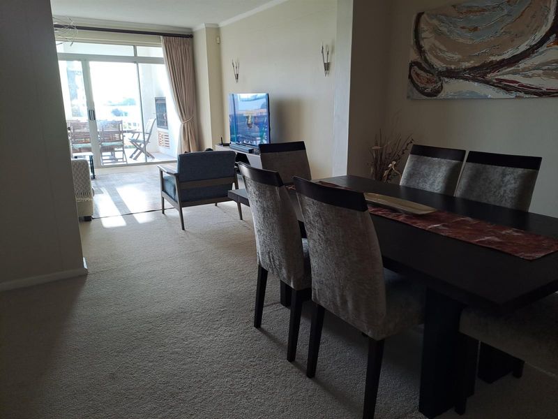 Open plan living and dining area featuring neutral carpeting and large sliding glass doors leading to a private balcony.