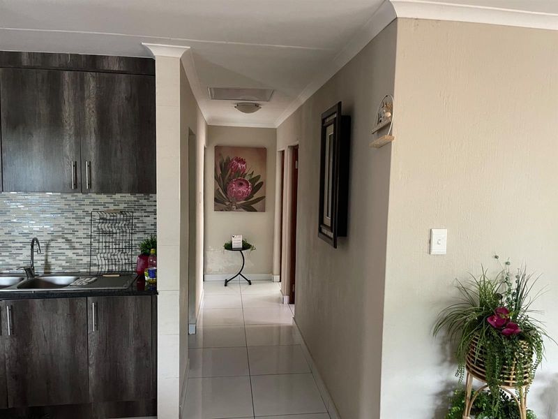 A view of a tiled hallway leading from a kitchen area with dark wood cabinetry and a mosaic tile backsplash.