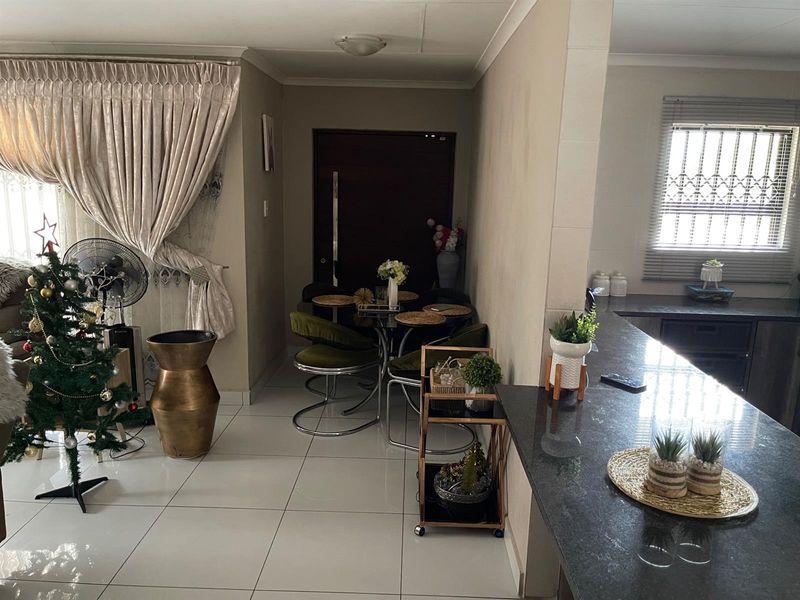 Open plan living and dining area featuring tiled flooring, a breakfast counter, and direct access to the entrance.