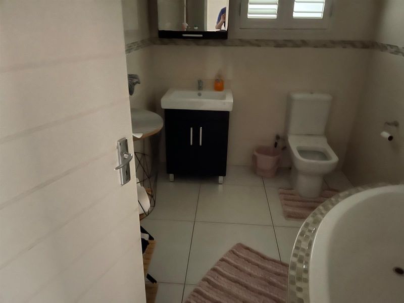 A functional bathroom featuring a vanity cabinet with integrated sink, a standard toilet, and a tiled floor finish.