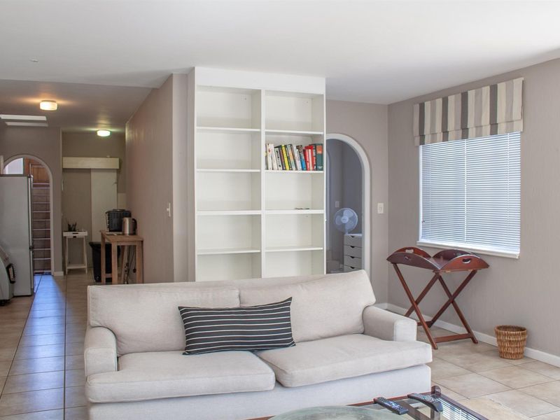 A living room featuring tiled flooring, a built-in shelving unit, and an arched doorway leading to an adjacent space.