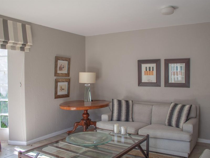 A comfortable living room featuring tiled flooring, neutral wall tones, and a glass-paned door providing natural light.