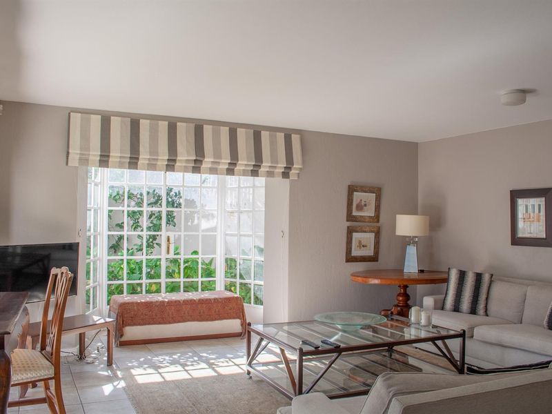 A bright and comfortable living room featuring tiled flooring and large french doors that provide direct access to the garden area.