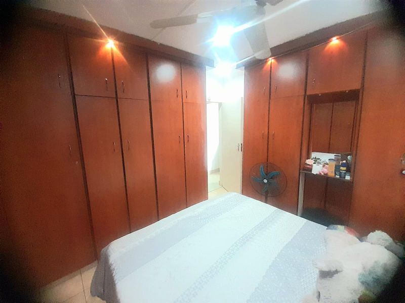 Bedroom featuring extensive floor-to-ceiling built-in wooden cabinetry with integrated lighting and a ceiling fan.