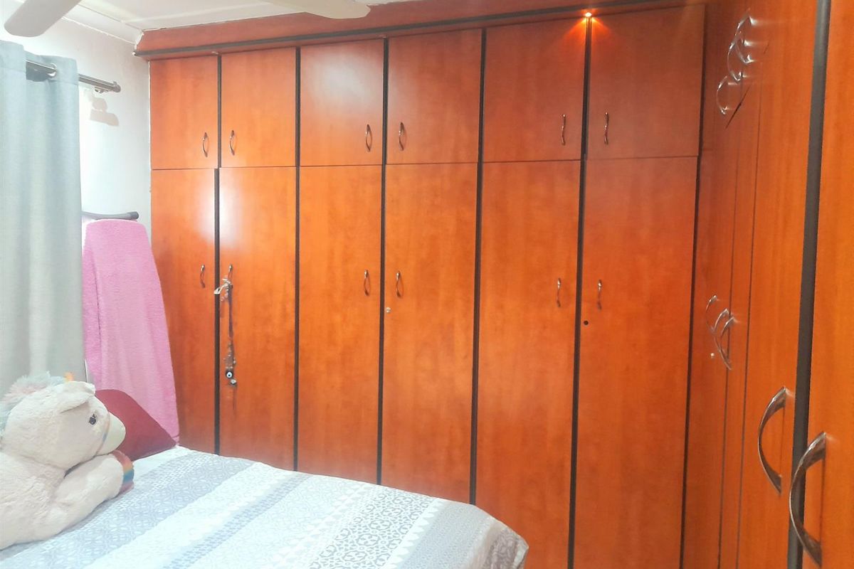 A bedroom featuring extensive floor-to-ceiling built-in wooden cupboards and a ceiling fan.