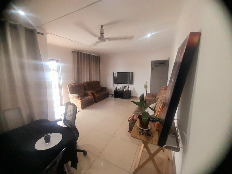 A spacious living room featuring tiled flooring, recessed lighting, and a ceiling fan, providing a functional and comfortable open-plan living area.