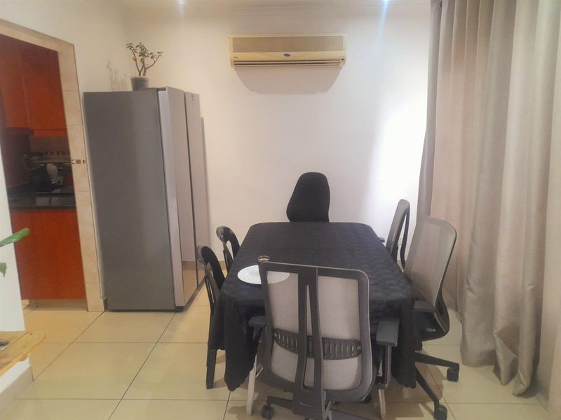 A dining area featuring tiled flooring and a wall-mounted air conditioning unit, providing a functional space adjacent to the kitchen.