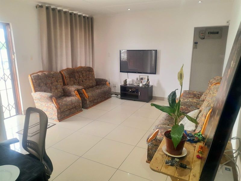 A functional living room featuring neutral tiled flooring and recessed downlighting, providing a clean and versatile space for relaxation.