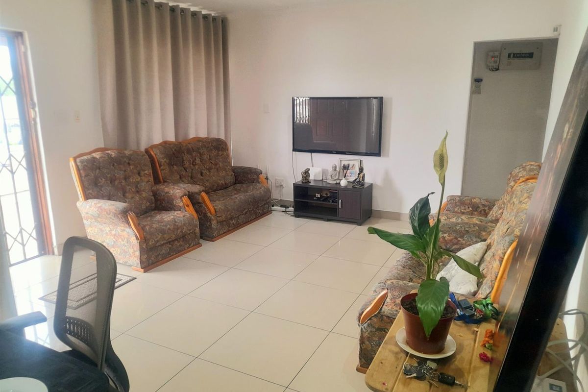 A functional living room featuring neutral tiled flooring and recessed downlighting, providing a clean and versatile space for relaxation.