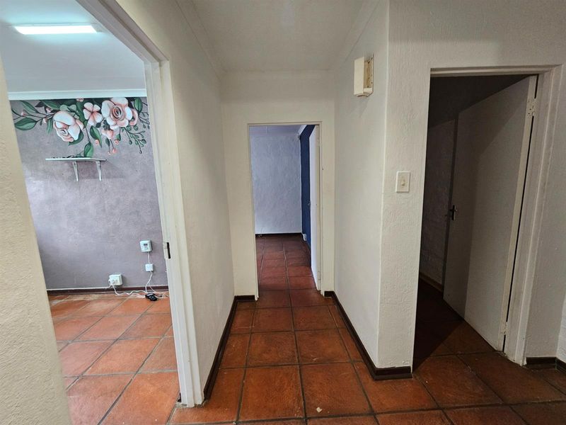 A central hallway featuring terracotta-style floor tiles, providing access to multiple rooms within the home.
