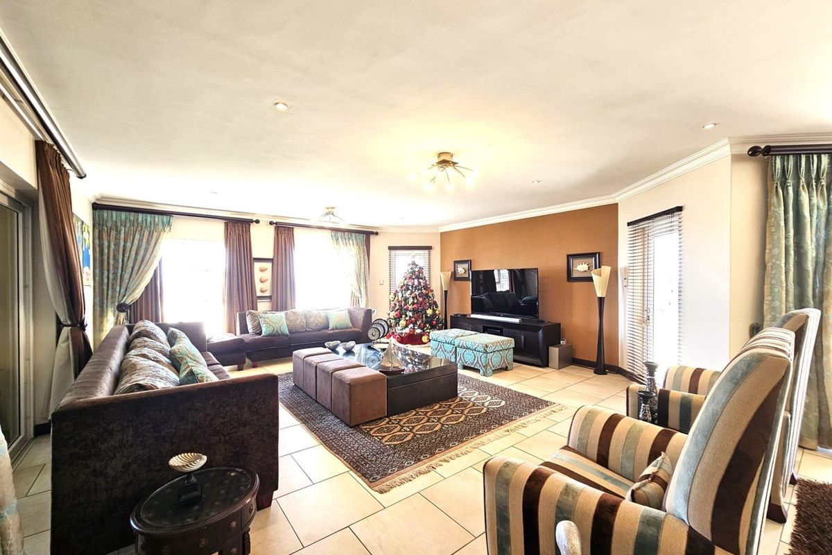 Spacious open-plan living area featuring large format floor tiles, recessed downlighting, and multiple access points to the balcony through sliding glass doors.