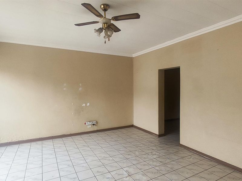 An empty living room featuring tiled flooring, a ceiling fan, and neutral wall finishes, offering a blank canvas for potential updates.