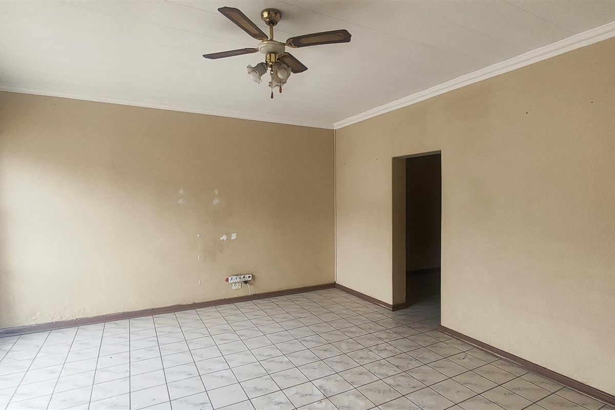 An empty living room featuring tiled flooring, a ceiling fan, and neutral wall finishes, offering a blank canvas for potential updates.