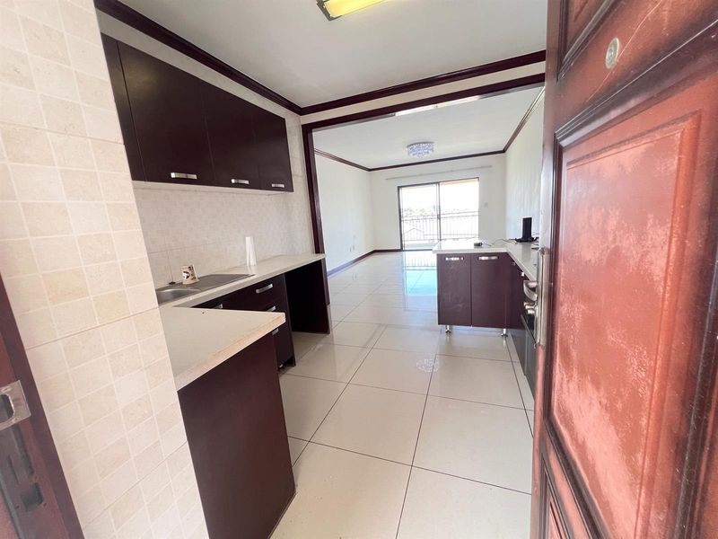 Open plan kitchen and living area featuring tiled flooring, dark cabinetry, and a sliding glass door leading to a balcony.
