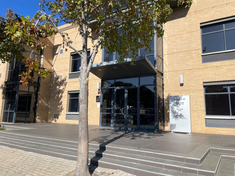 Front entrance view of Block D office building featuring a brick facade, glass entrance doors, and professional signage.