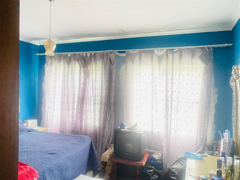 A bedroom featuring blue walls, a coved ceiling, and a pendant light fixture, currently requiring cosmetic updates to the wall finishes.